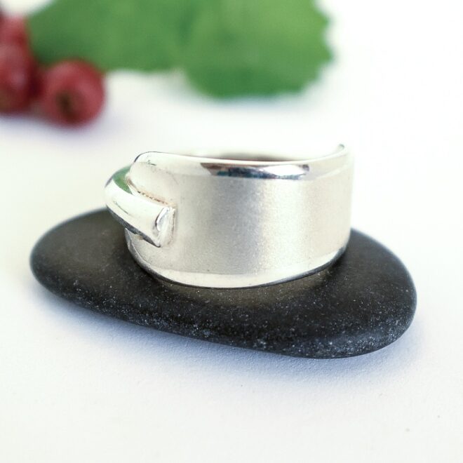 Matta-sormus, joka on taivutettu hopealusikan varsiosasta, niin että varren ohuempi pää on jäänyt kohokuvioksi sormuksen pinnalle.