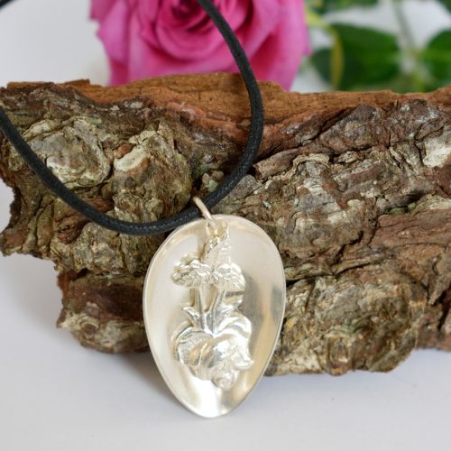 Auranruusu-riipus, joka designattu hopeisesta lusikanpesästä, johon juotettu varren ruusu koristeeksi.