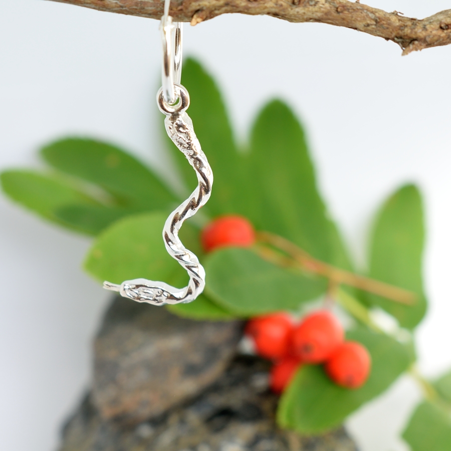 Käärme-korvakoru, joka on muotoiltu kierteisen hollantilaisen hopealusikan varsiosasta.