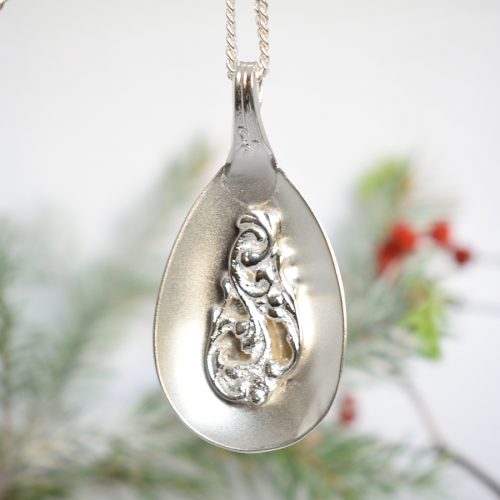 Ramona-riipus, joka on valmistettu hopeisen hillolusikan pesästä. Korun keskelle on koristeeksi juotettu saman lusikan varren pää.