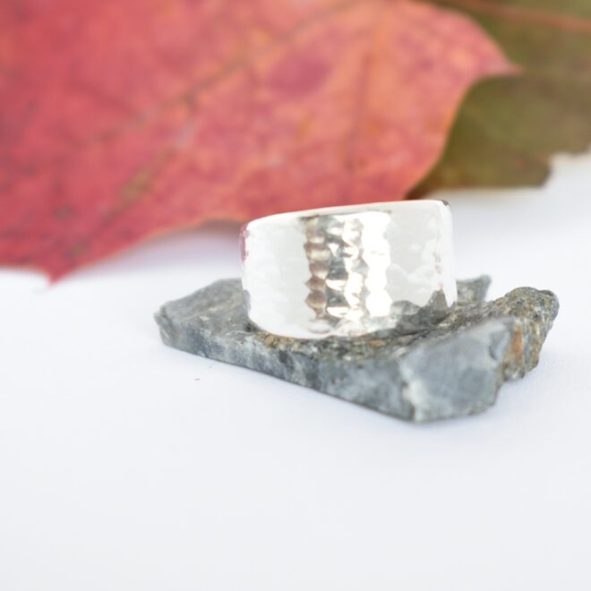 Läike-takosormus, joka on muotoiltu hopeisen sileävartisen lusikan varresta. Sormuksen pinta on kevyesti taottu.