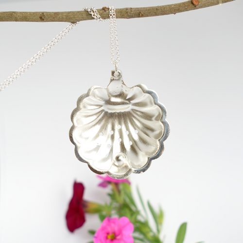 Helmisimpukka-riipus, joka on valmistettu hopeisesta Herman Wistin sokerisirotin-lusikan pesästä. Riipuksen alaosaan on juotettu Sterling-hopeahelmi.