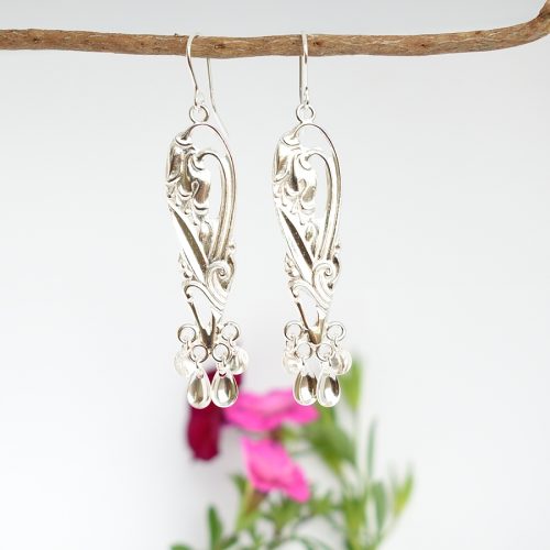 Lapinkello-korvakorut on muotoiltu hopeisten kahvilusikoiden varsista ja korujen alaosaan on lappilaisten korujen tyyliin kiinnitetty hopeisia laukkasia.