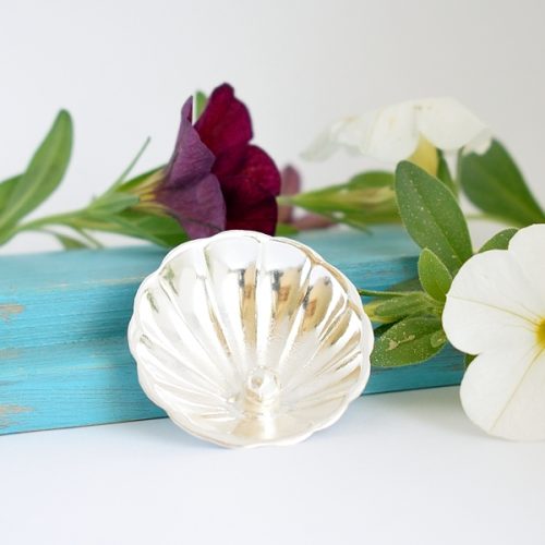 Helmisimpukka-rintaneula, joka on valmistettu hopeisen sokerilusikan pesästä. Pesään on juotettu hopeahelmi.