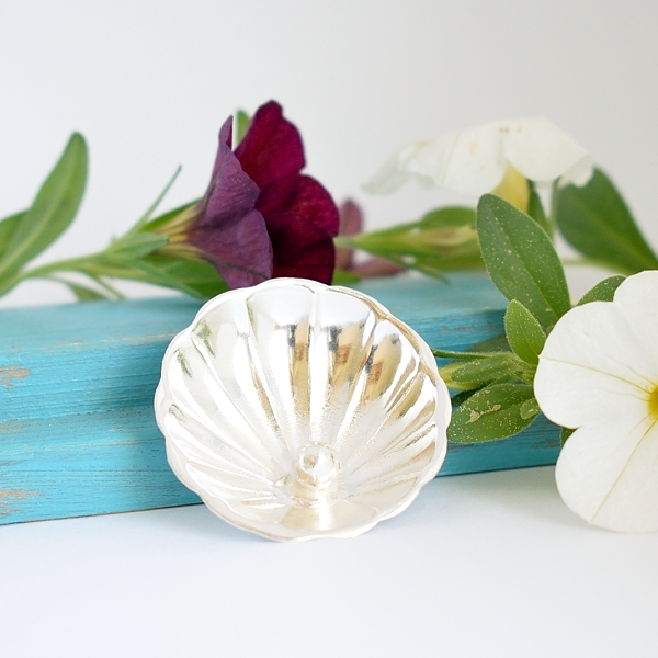 Helmisimpukka-rintaneula, joka on valmistettu hopeisen sokerilusikan pesästä. Pesään on juotettu hopeahelmi.