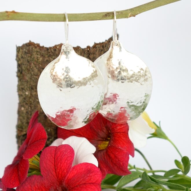 Kuunvalo-korvakorut, jotka on valmistettu hopeisten kahvilusikoiden pesistä. Korujen pinta on taottu.