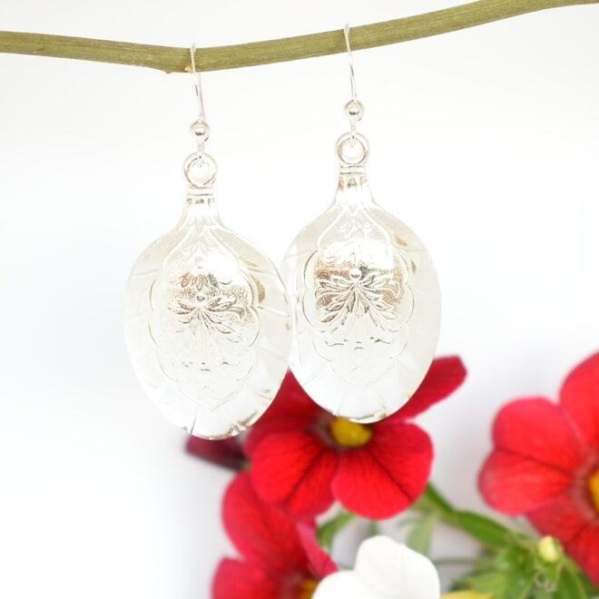 Lehdykät-korvakorut, jotka on valmistettu hopeisten, suomalaisten mokkalusikoiden pesistä. Pesissä on kaunis lehtikuviointi.