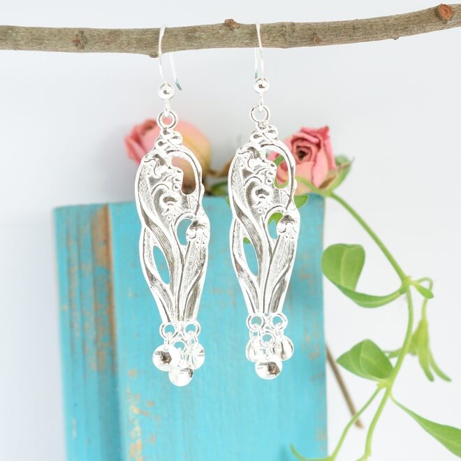 Kielot-korvakorut, jotka on valmistettu hopeisten, suomalaisten kahvilusikoiden varsista. Korujen alaosaan on kiinnitetty pieniä, hopeisia laukkasia lappalaiskorujen tyylin mukaisesti.