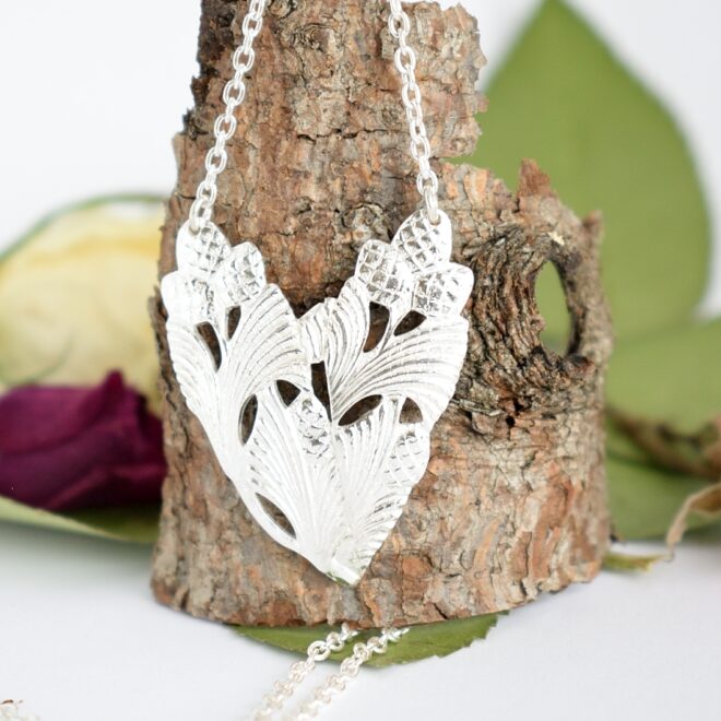 Sydänkäpy-riipus, joka on muotoiltu hopeisten Käpy-lusikoiden varsista sydämen muotoiseksi.