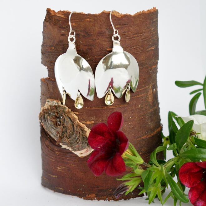 Kellokukka-korvakorut, jotka on muotoiltu hopeisten lusikoiden pesistä kellokukan muotoiseksi. Heteiksi on kiinnitetty pieniä, kullattuja laukkasia lapinkorujen tyylisesti.