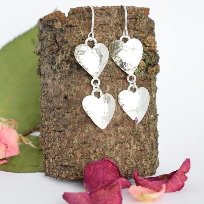 Tuplasydän-korvakorut, jotka on muotoiltu hopeisten lusikoiden pesistä. Koruihin on kiinnitetty kaksi taottua sydäntä peräkkäin. Koruissa on koukkukiinnitys