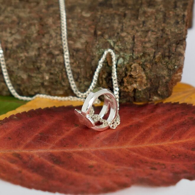 Lehti-kastesormus-riipus, joka on muotoiltu hopeisen lusikan varresta. Sormuksen renkaan halkaisija on 9,5 mm ja riipuksena sen koko on 12 x 7 mm.