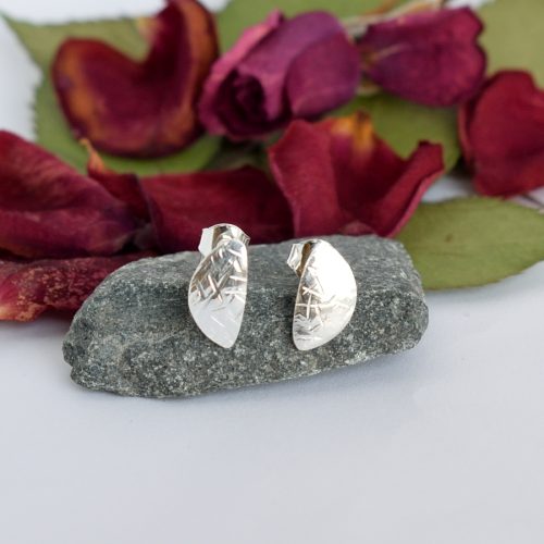 Puolikuu-korvakorut, jotka on muotoiltu hopealusikoiden pesistä. Korujen pintaan on taottu kaarnaa muistuttava kuvio.