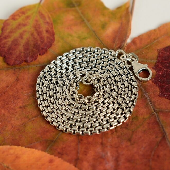 Kuvassa FBM Binder Box kaulaketju aseteltuna kiepille vaahteranlehden päälle.