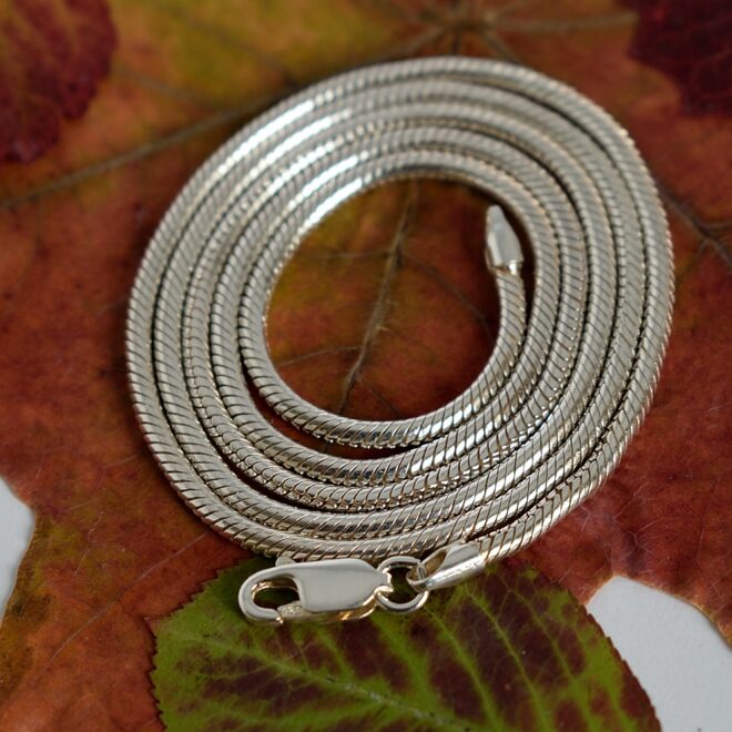 Kuvassa Käärme kaulaketju aseteltuna kiepille vaahteranlehden päälle.